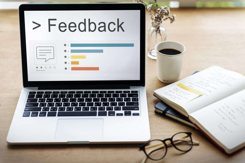 Laptop displaying feedback ratings on a workspace with coffee and notes