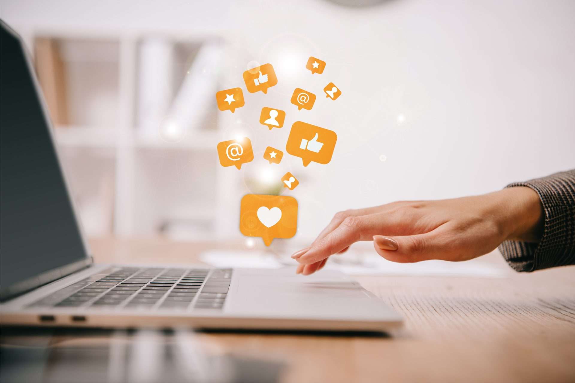 Person using a laptop with floating social media icons above the keyboard.